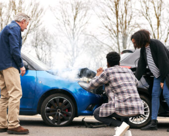 Young Couple Take Photos On Mobile Phone Of Damage To Car In Accident With Senior Driver